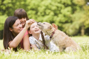 Mother and daughters in park with dog smiling